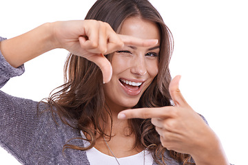Image showing Portrait, woman and wink with finger frame in studio to review profile picture on white background. Happy model, blink and check border with hands for photography, selfie and planning perspective