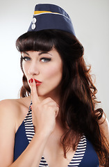 Image showing Travel portrait, silence and a sailor woman, model or girl in studio isolated on a white background. Finger on lips, face of vintage person in hat and hand sign for secret, makeup and fashion pin up