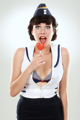 Image showing Portrait, surprise and sailor woman with lollipop in studio isolated on a white background. Candy, wow and shocked air hostess with sugar food, heart sweets or travel dessert for vintage pin up girl