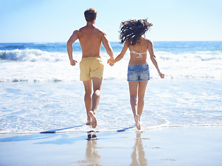 Image showing Couple, holding hands and running on beach for holiday, swimming in summer and vacation by ocean. Back of people in bikini with love, valentines day and fun in sun and water or sea for anniversary