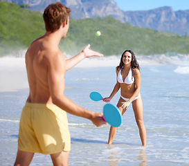 Image showing Travel, paddle ball and couple on beach together, having fun or playing game on holiday in summer. Love, smile or happy with young man and woman in water by sea or ocean for bonding in nature