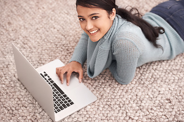 Image showing Portrait of happy woman on carpet with laptop, relax and browse with studying, research and web in living room. University student girl on floor with computer, elearning and online education in home.