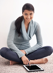 Image showing Portrait of happy woman sitting on carpet with tablet, smile and relax for studying, research and social media in living room. Student girl on floor with digital app, elearning or online blog in home