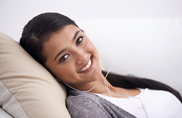 Image showing Portrait of happy woman on sofa with smile, headphones and relax with mobile app for podcast in house. Face of girl lying on couch with earphones, music and streaming service for online radio in home