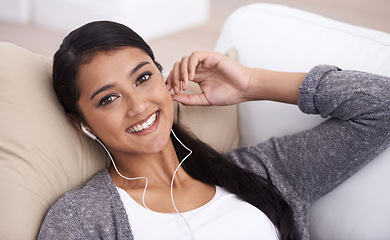 Image showing Portrait of happy woman on sofa with smile, earphones and relax with mobile app for podcast in house. Face of girl lying on couch with headphones, music and streaming service for online radio in home