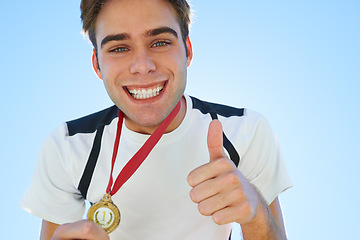 Image showing Winner, man and thumbs up with medal for sports achievement, success and yes in competition. Happy portrait of runner or athlete with like, prize or good job hands, emoji and gold award on a blue sky