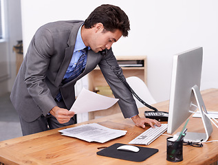 Image showing Businessman, phone call and multitasking on computer in office, networking and technology in workplace. Young accountant, talking or landline with paperwork, consultation or finance advice in company
