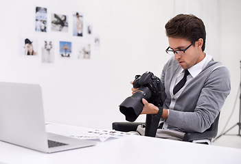 Image showing Man, camera and photography in office with laptop, checking image batch and creative in workplace. Person, thinking and glasses for vision, technology and focus in agency with professional career