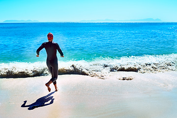 Image showing Swimming, back and woman running to sea at beach in summer for exercise, training or workout on mockup space. Ocean, sport and rear view of athlete at water outdoor for fitness, health or triathlon