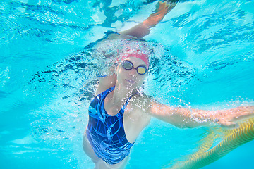 Image showing Underwater, woman and swimming with workout, stroke and sports with exercise, healthy and active. Person, wet and athlete with fitness, competition and indoor pool with wellness, breathing and splash