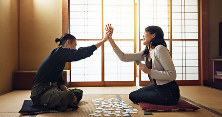 Image showing Man, woman and game with cards, high five and challenge on floor, contest or problem solving with clue. People, couple and karuta for competition with paper, reading and celebration for win in home