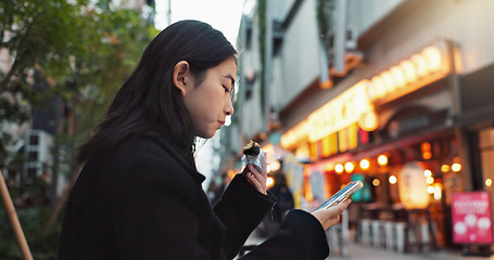 Image showing Phone, eating and Asian woman with onigiri in the city on exploring vacation, adventure or holiday. Hungry, food and young female person enjoying a Japanese snack or meal in town on weekend trip.