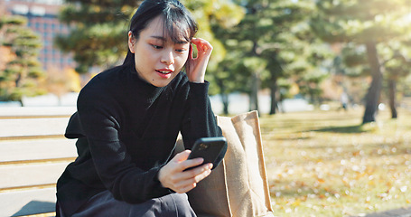 Image showing Happy asian woman, phone and sitting on park bench for social media, communication or networking. Female person smile in relax on mobile smartphone for online search, streaming or reading in nature