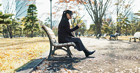 Image showing Asian woman, walking and relax on park bench with phone for social media, communication or networking. Female person sitting with mobile smartphone for online search, streaming or break in nature