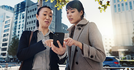 Image showing Phone, city and Japanese business woman planning together for travel, journey or commute. Collaboration, talking or discussion with employee team reading text message communication outdoor in Tokyo