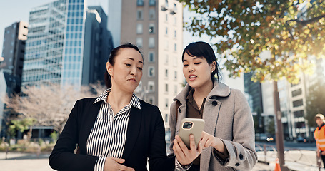 Image showing Phone, city and Japanese business woman walking to work together for travel, journey or commute. Collaboration, planning and discussion with employee team reading text message outdoor in Tokyo