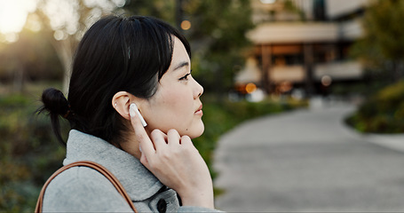 Image showing Japanese woman, earphones and walk in city with listening, music and streaming subscription on road. Girl, person and audio tech for podcast, radio and sound with travel on metro sidewalk in Tokyo