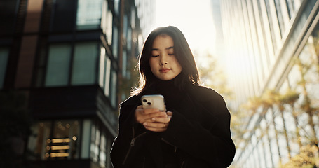 Image showing Walking, phone and Japanese woman in the city networking on social media, mobile app or the internet. Travel, adventure and young female person commuting in road with cellphone town in Kyoto Japan.