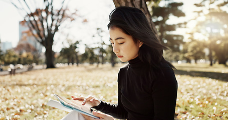 Image showing Japanese woman, reading and book on lawn, thinking and relax by tree, park or sunshine with peace. Girl, person or student with story in nature, college or idea with vision, knowledge or campus grass