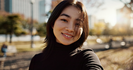 Image showing Japanese woman, happy and portrait in park, nature and path with sunshine, city and buildings with pride. Girl, person and smile by lawn, grass and trees in urban metro, outdoor and travel in Tokyo