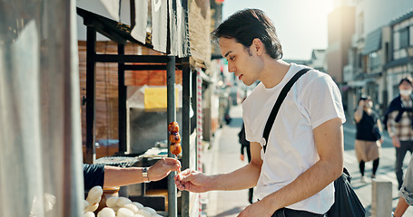 Image showing Man, food and street vendor with kebab on travel, walk or tourism for taste test, culture and giving product. Person, customer and shop for snack on metro sidewalk, vacation and urban road in Japan