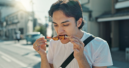 Image showing Man, street food and eating kebab in city on travel, walk and tourism with taste test, culture and lunch. Hungry person, guy and snack on metro sidewalk, vacation and thinking on urban road in Japan