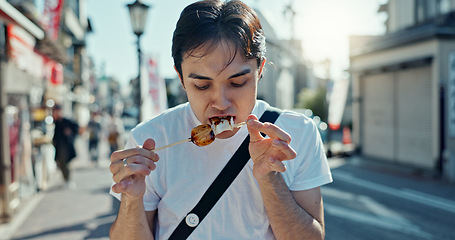 Image showing Man, street food and eating kebab on walk on travel, city and hungry for goheimochi with nutrition, diet or lunch. Person, rice snack and skewer on metro sidewalk, vacation and urban road in Japan