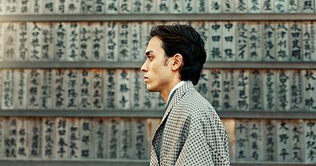 Image showing Outdoor, walking and wall with man, Japan and calligraphy with peace, choice and thinking. Person, calming and guy with traditional clothes, travel and decision with thoughts, wonder and aesthetic