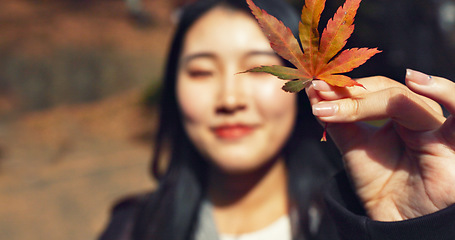 Image showing Woman, Asian and face with leaf in autumn, nature and color with happiness outdoor. Environment, plant and smile in portrait, park or garden in Japan with foliage, mockup space and positivity