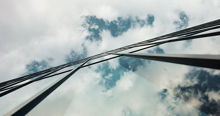 Image showing Low angle, skyscraper building and clouds in city with reflection, nature and urban infrastructure. Architecture, cityscape and skyline and metro with landscape, glass and sky background in timelapse