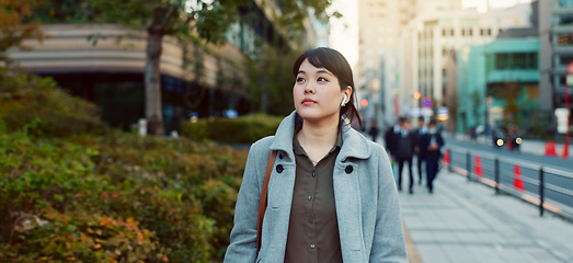 Image showing Woman, Asian and walking, travel or commute to work with professional in city with earphones. Listening to music on journey, podcast and commuter on urban street or sidewalk in Tokyo with playlist