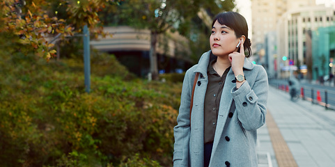 Image showing Woman, Asian and walk on sidewalk, travel or commute to work with professional in city with earphones. Listening to music on journey, podcast and commuter on urban street in Tokyo with playlist