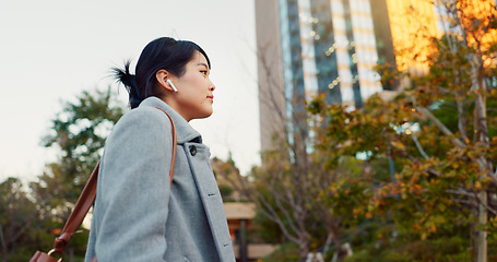 Image showing Woman, Asian and earphones, travel in city and commute to work with radio or podcast outdoor. Technology, spin and listening to music on journey, urban street and professional walking outdoor