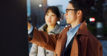 Image showing Conversation, night and young Asian couple in the city for travel, adventure or journey together. Communication, happy and man and woman talking by board for commuting in urban town in evening.