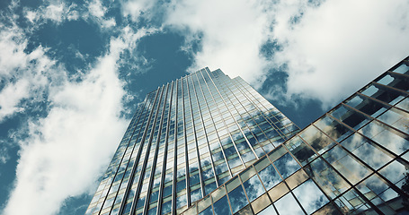 Image showing Low angle, skyscraper building and clouds with reflection, nature or urban infrastructure in city. Architecture, cityscape and skyline and metro with landscape, glass and sky background in timelapse