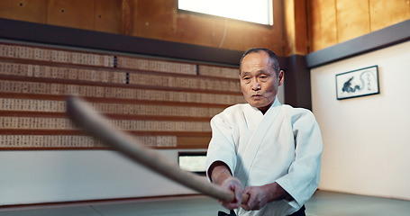 Image showing Aikido sword, martial arts and mature man strike for training, self defense or combat technique. Dojo, Japanese person and expert with wooden weapon for skills development, attack or bokken practice