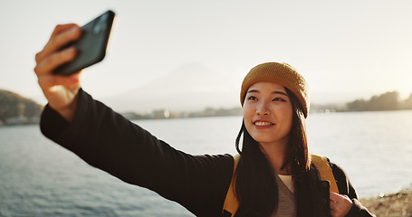 Image showing Selfie, travel and Japanese woman by lake for holiday, vacation and adventure in Japan. Happy, smile and person take picture on smartphone by water for social media post, memories and online blog