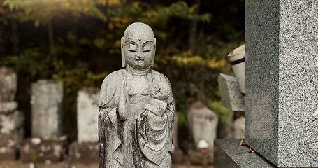 Image showing Buddha, statue in Japan graveyard with child for safety, protection and sculpture outdoor in nature. Jizo, tombstone and memorial gravestone with history, culture and monument for sightseeing or trip