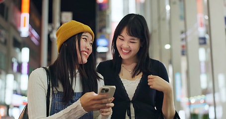 Image showing Woman, friends and Japanese or cellphone in city street for night communication, research or location. Female person, Tokyo road and lights internet network for social media news, adventure or travel