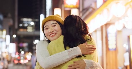 Image showing Woman, friends and hug in Japanese city or happy reunion for party night, adventure or Tokyo. Female people, embrace and dark or bokeh on street with light or international travel, journey or evening