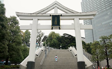 Image showing Back, shrine and steps with Japanese woman walking in city temple for belief, faith or religion. Building, worship and location with person on stairs in Tokyo for tradition, mindfulness or adventure