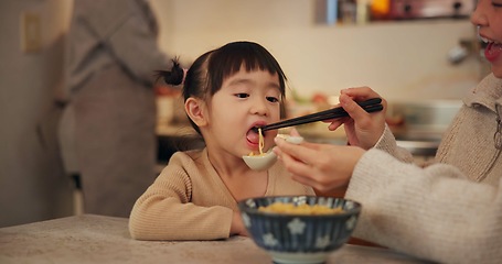 Image showing Family, Japanese and woman feeding daughter in kitchen of home for growth, health or nutrition. Food, girl eating ramen noodles in apartment with mother and parent for diet or child development