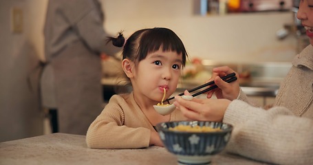 Image showing Family, japanese and woman feeding daughter in kitchen of home for growth, health or nutrition. Food, girl eating in Tokyo apartment with mother and grandparent for diet or child development