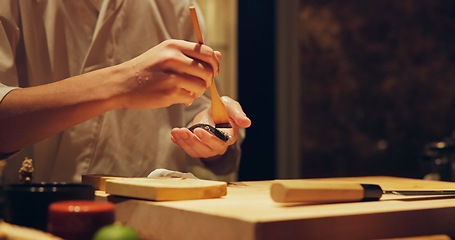 Image showing Hands, food and chef cooking sushi in restaurant for traditional Japanese cuisine or dish closeup. Kitchen, table for seafood preparation and person working with gourmet meal recipe ingredients