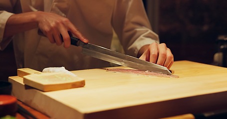 Image showing Hands, food and chef cutting sushi in restaurant for traditional Japanese cuisine or dish closeup. Kitchen, cooking seafood for preparation and person working with gourmet meal recipe ingredients