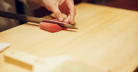 Image showing Hands, food and sushi chef cutting fish in restaurant for traditional Japanese cuisine or dish closeup. Kitchen, cooking on table for seafood preparation and person working with gourmet ingredients