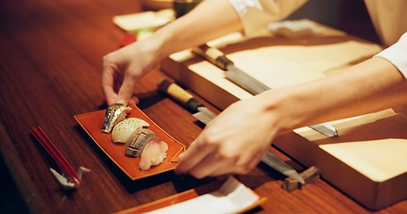 Image showing Hands, cooking and chef serving sushi in restaurant for traditional Japanese cuisine or dish closeup. Kitchen, service or preparation of seafood and person working with gourmet recipe ingredients