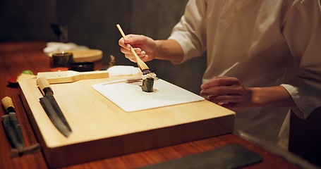 Image showing Hands, food and sushi with cook in restaurant for traditional Japanese cuisine or dish closeup. Kitchen, table for seafood preparation and professional chef working with gourmet recipe ingredients