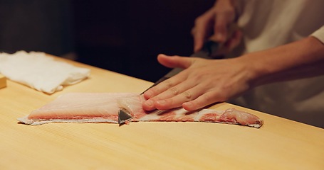 Image showing Hands, food and sushi chef cutting fish in restaurant for traditional Japanese cuisine or dish closeup. Kitchen, raw seafood preparation and person working with gourmet meal recipe ingredients