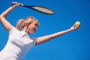 Image showing Tennis, serving and woman in game for sport, competition and playing with ball and racket on blue sky. Athlete, exercise and training outdoor with challenge on court in summer match and contest